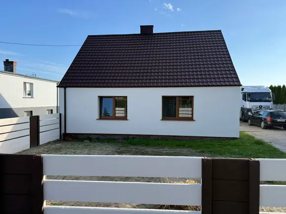 Dom jednorodzinny po wykonaniu elewacji — białe ściany, nowa stolarka i dach